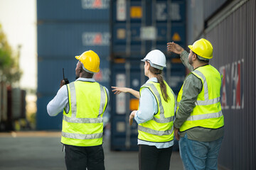 Group of workers in the import and export industry use walkie talkies to communicate with drivers...