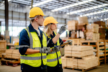 workers man and woman engineering walking and inspecting timbers wood in warehouse. Concept of...