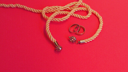 Tying the knot: silkly rope and two silvery rings, with a pink background