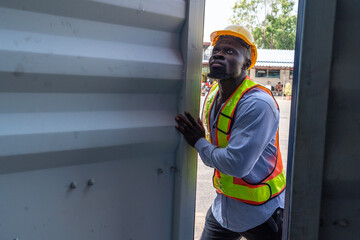 Black man working in container yard opening container door