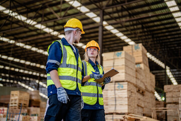 workers man and woman engineering walking and inspecting timbers wood in warehouse. Concept of smart industry worker operating. Wood factories produce wood palate.