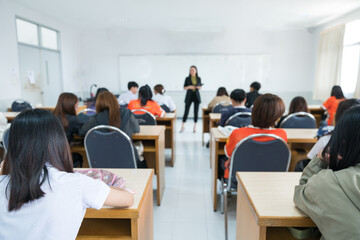 Rearview of college students listening to lecturer in the classroom