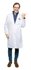 Middle age therapist wearing white coat smiling with happy face looking and pointing to the side with thumb up.
