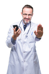 Middle age senior hoary doctor man texting using smartphone over isolated background with open hand doing stop sign with serious and confident expression, defense gesture