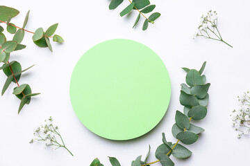 Bright green cosmetic podium and fresh eucalyptus twigs on white background close up. Cosmetic...
