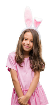 Brunette hispanic girl wearing easter rabbit ears with a happy face standing and smiling with a confident smile showing teeth