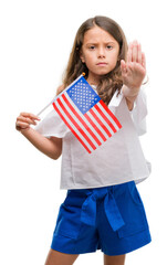 Brunette hispanic girl holding flag of United States of America with open hand doing stop sign with...