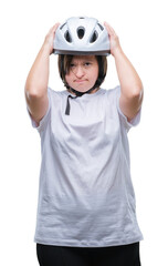 Young adult cyclist woman with down syndrome wearing safety helmet over isolated background suffering from headache desperate and stressed because pain and migraine. Hands on head.