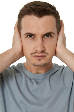caucasian man in t-shirt covers ears with hands on white background