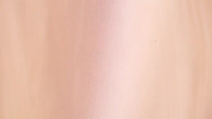 Liquid shiny cosmetics product with bubbles in peach fuzz colour, macro, top view. Beige or light orange shower gel rotation. Slow Motion, Abstract art