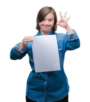 Young adult woman with down syndrome holding blank paper sheet over isolated background doing ok sign with fingers, excellent symbol