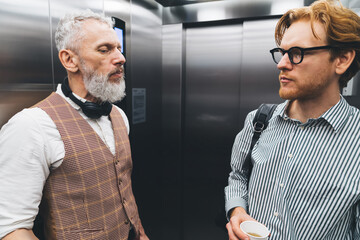 Serious matured businessmen standing in elevator