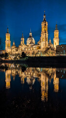 Fototapeta na wymiar Crescent Serenade: The Basilica del Pilar, moonlit Zaragoza sky, and Stone Bridge create a mesmerizing nocturnal harmony, with the Ebro River reflecting the enchanting beauty of this Spanish city. 
