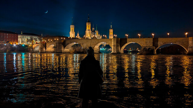 Nocturnal Reverie: Mesmerizing reflections surround a woman, harmonizing with Zaragoza's iconic landmarks.
