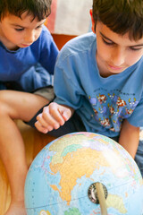 Boys looking at earth globe in the house