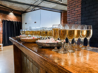 Bar counter with glasses of champagne, sparkling wine stands in transparent glass glasses on the bar.