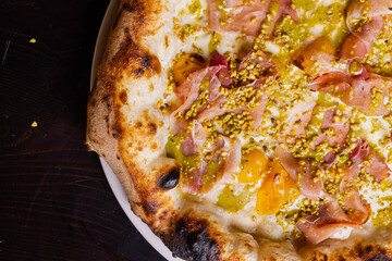 Pizza tradizionale napoletana con mortadella, pomodorino giallo, mozzarella e granella di pistacchio servita in una pizzeria