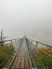 Suspended bridge covered in fog. Foggy weather.
