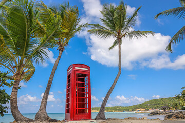 Traditional English red telephone booth on a the beach of Dickenson Bay on Antigua Island. 