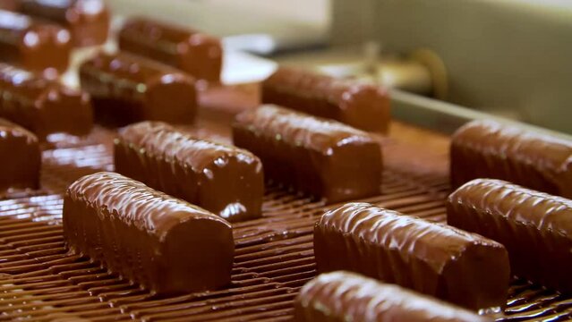 Candy production. Candy on the conveyor. Chocolate pouring. Conveyor belt in a chocolate factory. Chocolate bars move along the conveyor belt in the confectionery factory for confectionery production.