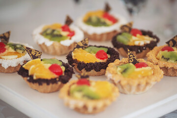 Candy bar with different assortments of cakes. Delicious sweets on wedding candy buffet with desserts, cupcakes. Desserts, different types of sweet pastries small colorful sweet cakes
