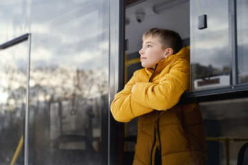 Side view of funny child male looking at blue cloudy sky standing crossing arms leaning on window...