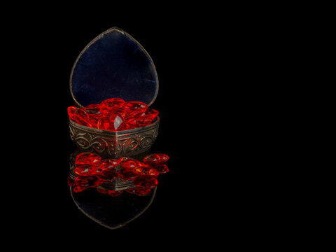 antique silver case filled with ruby red hearts for valentines day isolated on a black background