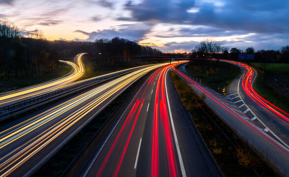 Major autobahn crossing of A40 and A3 in Ruhr Basin Germany near Duisburg, Oberhausen, Essen and D&uuml;sseldorf. Panoramic longtime exposure with red and white lights of passing cars at dusk blue hour.