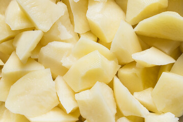 A close-up of freshly cut raw potatoes, their texture glistening with moisture, ready for cooking. Food and textures.