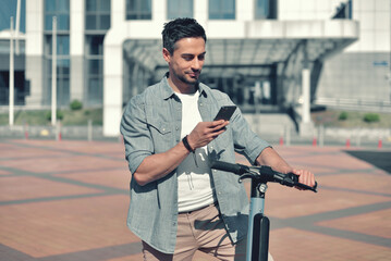 Mobility and freedom. A fashionable young man on an e-scooter smiles and looks at his modern smartphone while strolling on a sunny square against the backdrop of urban architecture