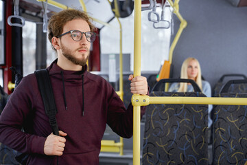 Close up of pensive adult male standing looking at window in public transport. Crop of cute young...