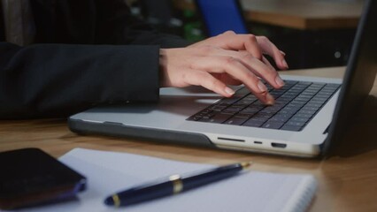 Businesswoman types proposals for potential clients customizing details on modern laptop. Professional office worker types messages to team members and reviews reports using device at table