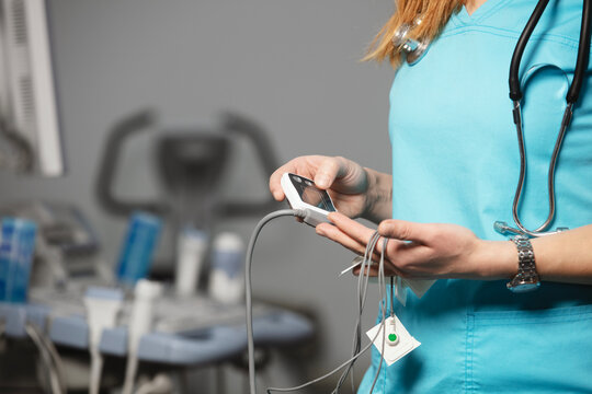 Doctor showing ECG holter monitor to patient in pediatric clinic. Holter monitoring device in a doctor hands before a diagnostic. Preparation for a heart rhythm diagnistic. Professional medicine.