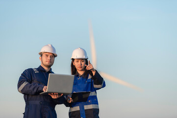 Two engineers working and holding the report at wind turbine farm Power Generator Station on...