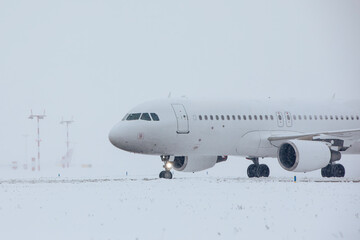 Traffic at airport during snowfall. Passenger airplane taxiing to runway for take off on frosty...