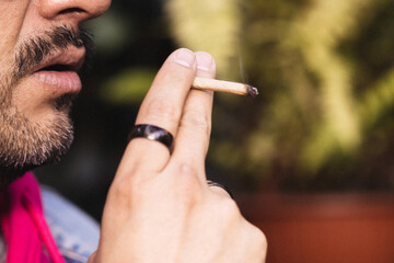 Detail of hands and mouth of a man smoking a marijuana cigarette.