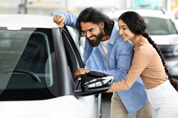 Fototapeta premium Happy Indian Spouses Looking Inside Of Their New Car Together