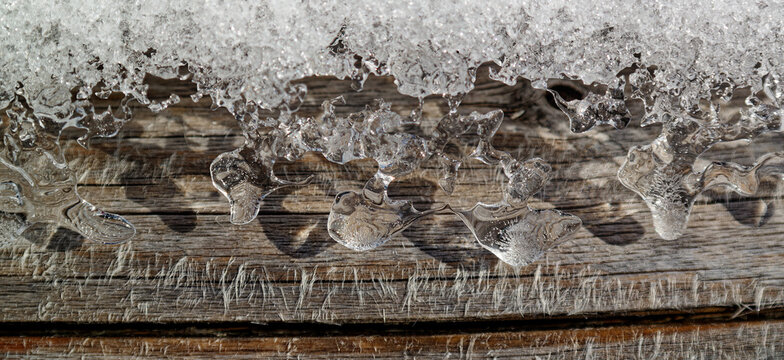 Winter wonderland, small pieces of ice on a wooden beam glitter in the sun, macro photo