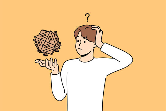 Confused man with wooden puzzle scratches head, wondering how to solve difficult problem. Thoughtful guy with puzzle needs help to find solution due to lack of necessary qualifications