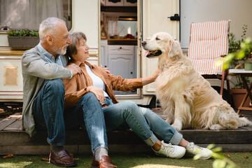 Happy old senior caucasian couple spouses traveling with their dog golden retriever labrador in...