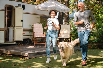 Active seniors concept. Caucasian old elderly couple family grandparents walking their dog running...