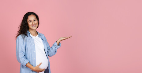 Cute young expecting lady pointing at copy space