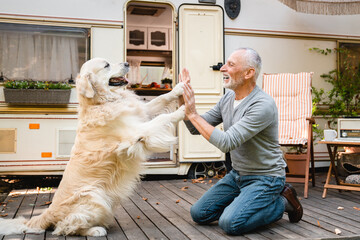 Pet owner old man senior traveler playing with his dog golden retriever labrador outdoors outside,...