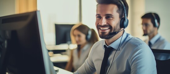 Male employee in call center with colleagues, wearing a headset. - obrazy, fototapety, plakaty