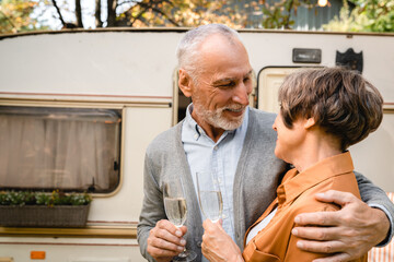 Loving tender old senior couple hugging celebrating with wine toasting anniversary while traveling...