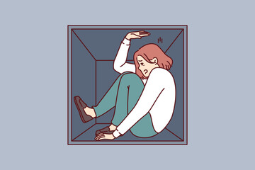 Woman suffering from claustrophobia sits in cramped box and feels pressure of walls, as metaphor for cramped housing. Girl experiences problems due to claustrophobia and fear of closed spaces.