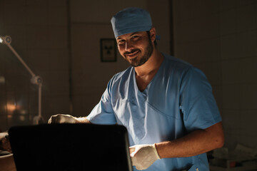 Smiling doctor looking at camera while performing an ultrasound in low light.