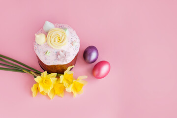 Traditional russian Easter ortodox cake with daffodil flower and colorful eggs on light pink background. Kulic, Kulich, Paska homemade bread with glaze. Spring christian holiday. Festive celebration