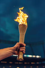 Hand holding flaming Olympic torch with Olympic stadium in the background