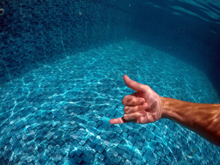 mão fazendo sinal de beleza em água de piscina 